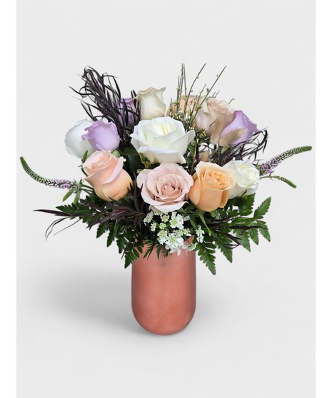 Vintage Garden style roses designed in a pink dimple pattern Vase. Antique hues of Lavender, pink and cream Roses mixed with seasonal cut garden accents. 