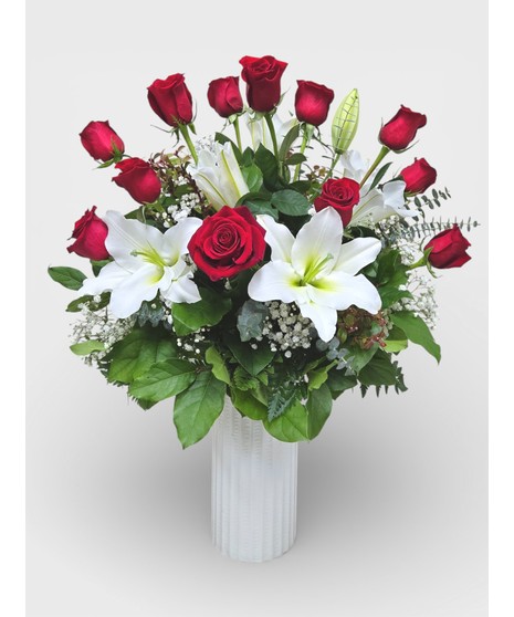 A dozen roses are complimented by the beauty and sweet scent of fragrant white lilies. 