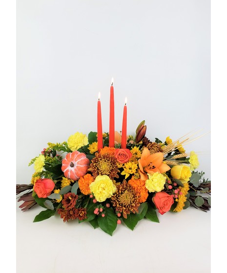 This arrangement is expertly crafted with vibrant orange lilies, golden sunflowers, roses, carnations, mums and fall texture.