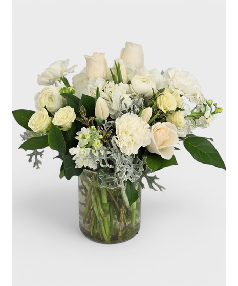 A beautiful mix of roses, lilies, and hydrangea with delicate filler flowers, designed in a clear cube vase.