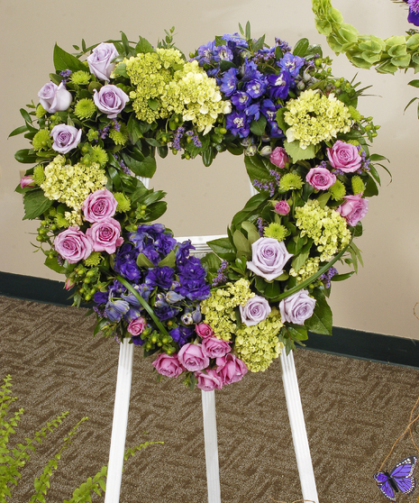Heart shaped sympathy tribute is a loving statement for any service. Featuring roses, hydrangea and other premium accents in shades of purple, green, pink, and blue. 