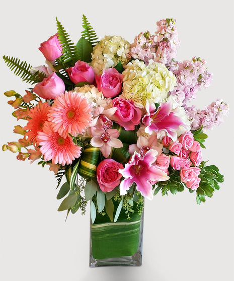 This beautiful design in shades of pink features our leaf wrapped signature clear vase. Lilies, roses, and hydrangea are among other floral textures and elegant greenery 