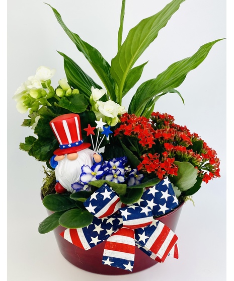 A festive red planter filled with red, white and blue indoor plants and a keepsake Uncle Sam gnome. 