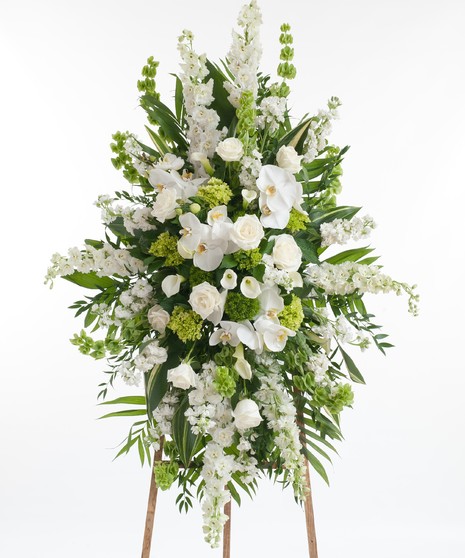 Premium collection of our finest white and green blooms featuring white roses, orchids, calla lilies, hydrangea, and other premium accents displayed on an easle. 