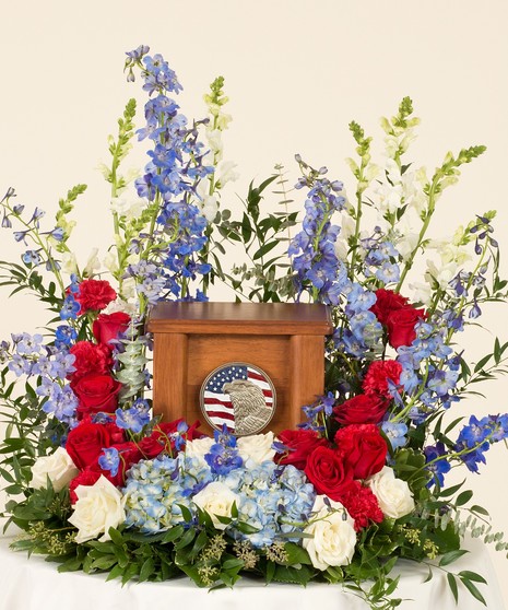 Memorial display featuring a patriotic mix of our favorite red white and blue flowers. This arrangement is designed for an urn placement. Family to provide urn .