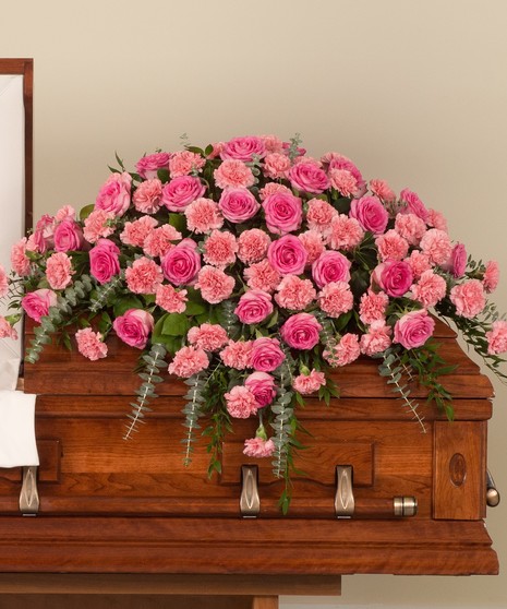 Delicate mix of pink roses and pink carnations with lush greens designed for the casket.