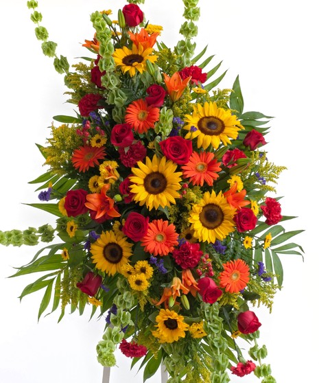 Stunning mix of sunflowers, lilies, roses, and other accent flowers in our popular Tuscan mix displayed on an easel. Approximate size of  the standard design is 28