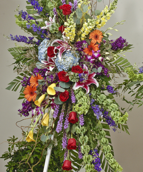 Vivid and bright easel display featuring lilies, hydrangea, gerbera daisies, and roses. Approximate size of the standard design is 28
