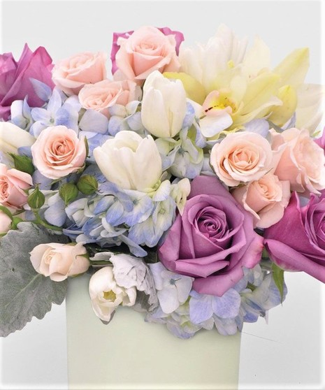Featuring roses, tulips, and orchids, this arrangement is crafted in a clear glass cube or hand-crafted purple glass cylinder.