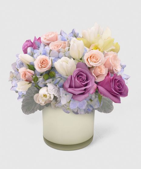 Featuring roses, tulips, and orchids, this arrangement is crafted in a clear glass cube or hand-crafted purple glass cylinder.