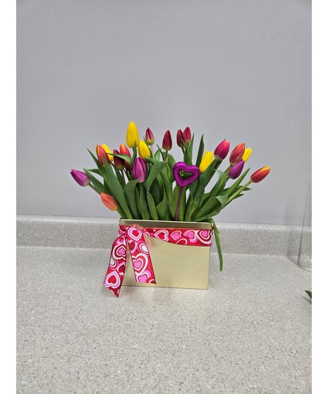 A mix of pink, white, purple, and red tulips in a rectangle vase with gems at the bottom.
